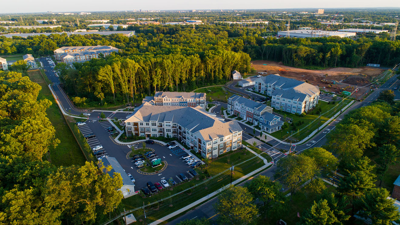 Aerial of a multi-building multifamily community surrounded by trees