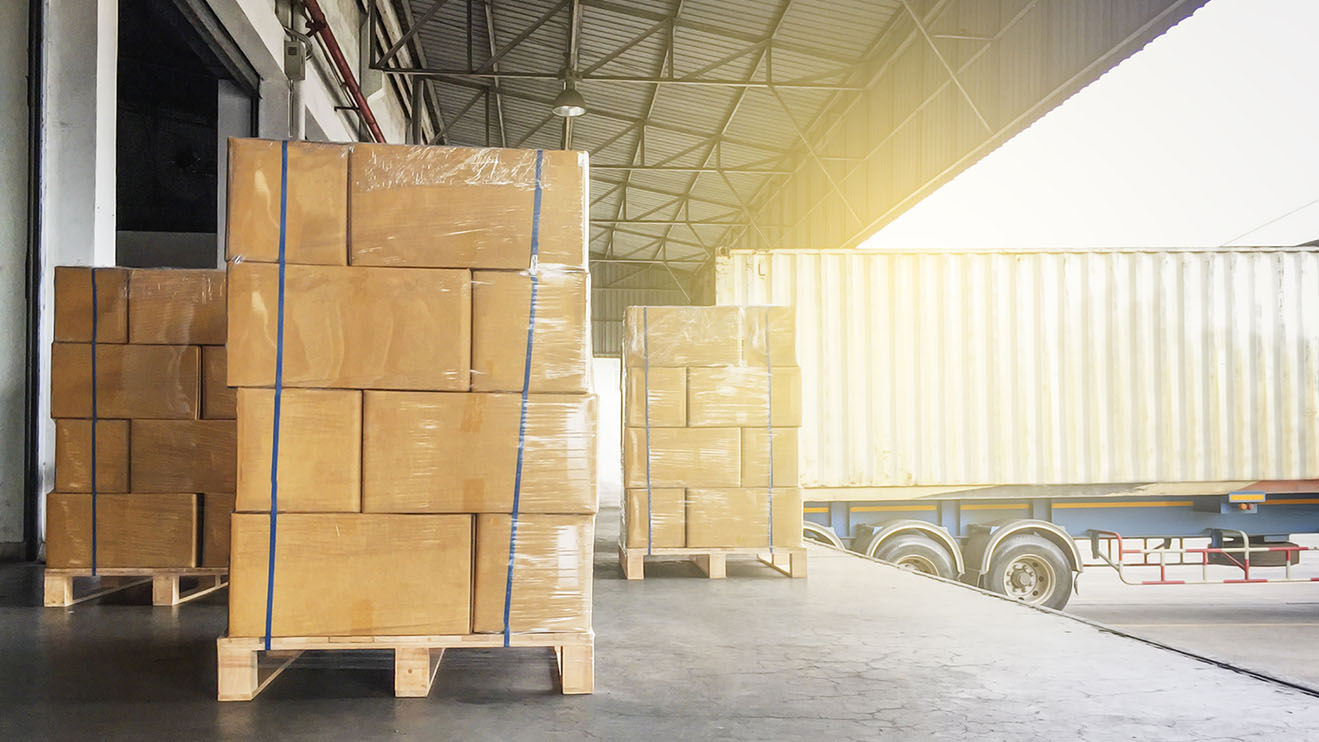 Warehouse cargo courier shipment. Stack of cardboard boxes on wooden pallet and truck docking at warehouse