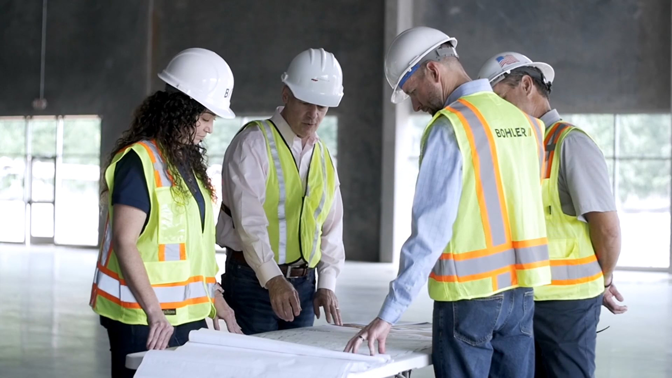 Engineers and contractors looking at a set of development plans in a warehouse