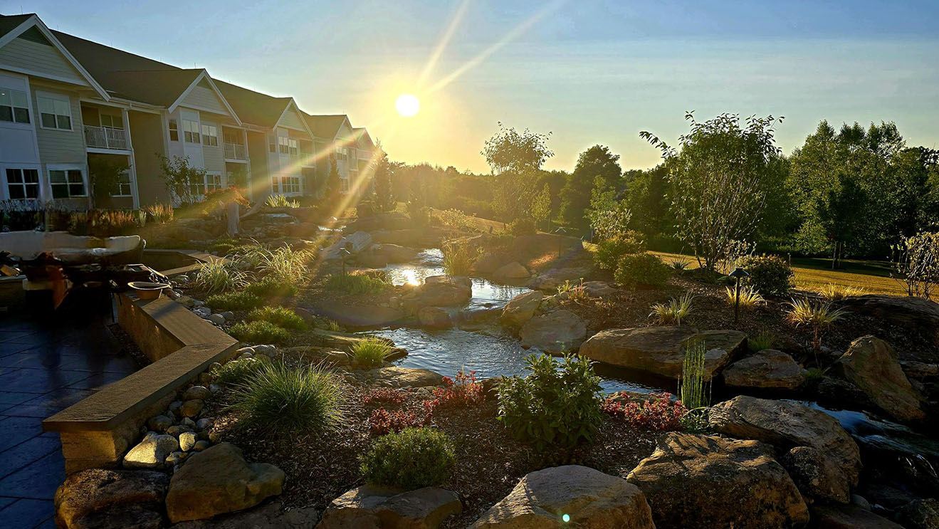 A beautifully landscaped amenity space with water feature at dusk