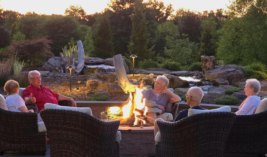 A group of elderly people sitting around a fire table talking