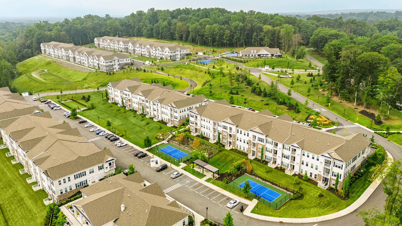 Birds eye view of a multi-building multifamily community showing pickleball courts and walking paths