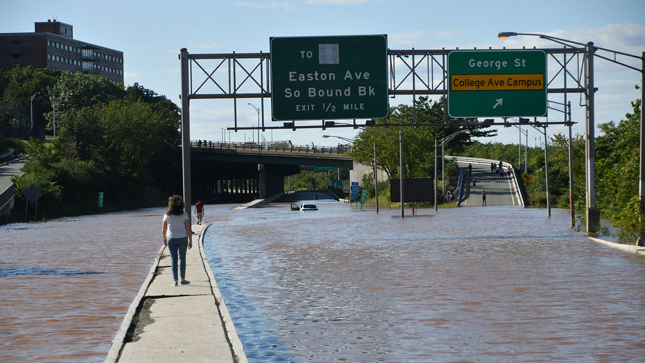 Woman walks on median in the middle of a flooded route 18 highway in New Brunswick, NJ after Hurricane Ida. New Brunswick, NJ USA - September 2, 2021: City of New Brunswick flooded after Hurricane Ida.